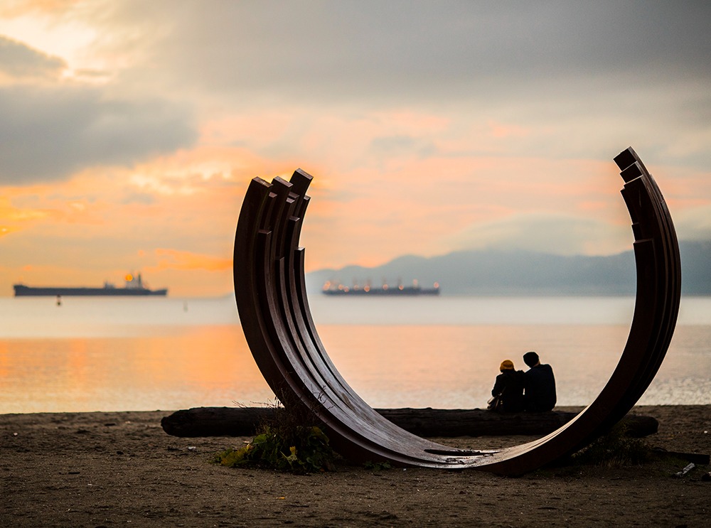 People sitting and watching the sunset on English Bay, Vancouver